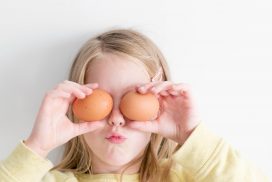 En ung lys jente holder to egg foran øynene sine